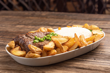 Beef steak with rustic potato and ricei on wooden table background, soft light