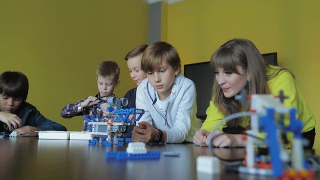 Kids creating figures with teacher. Early development, modern technology concept