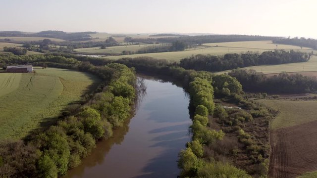 Beauitful river landscape. Aerial shot flying, descending over river, farmland in background