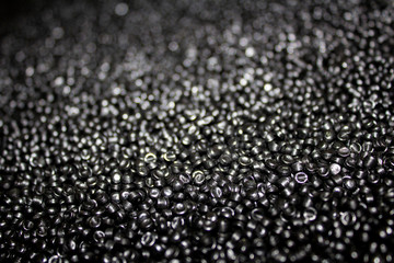 surface made of black plastic granules with a clear focus in the foreground and with a defocused background.