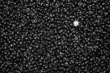 A plane filled with black plastic granules with one white granule.