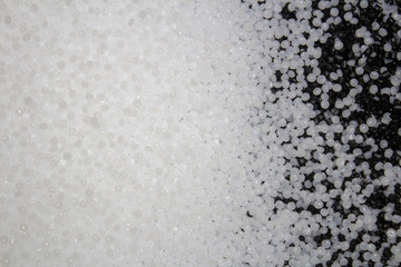 white plastic granules with black granules mixed with them on the right.