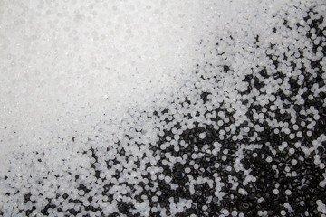 white plastic granules with black granules mixed with them to the right and bottom.