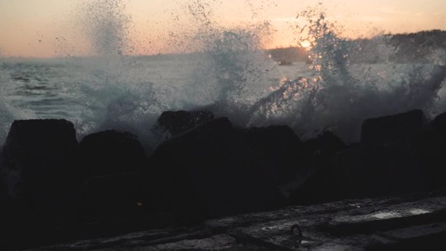 Sea waves in a storm on a cold day, slow motion . Ocean waves are breaking on a breakwater at sunset