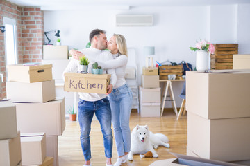Fototapeta premium Young beautiful couple with dog moving cardboard boxes at new home