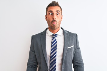Young handsome business man wearing suit and tie over isolated background making fish face with lips, crazy and comical gesture. Funny expression.