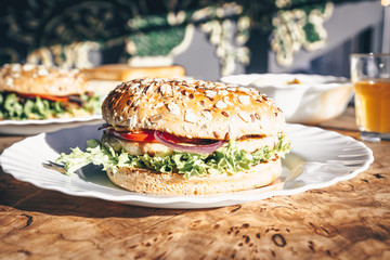 Chicken burgers on wooden slab table on food cort. Sunny day. Street food. Selective focus. Fastfood concept