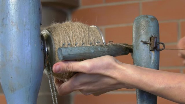 Rotating spindle in a manual woolen lock during operation. Extra close-up hand-operated spindle parts in action.