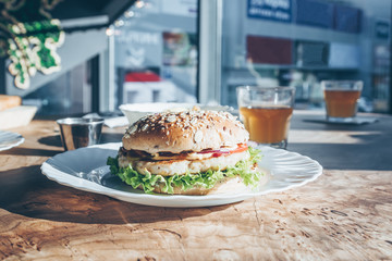 Chicken burgers on wooden slab table on food cort. Sunny day. Street food. Selective focus....