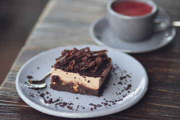 A metal teapot with rose tea in a restaurant. Tea party with chocolate dessert in a cafe. Vitamin raspberry tea with mint and cheesecake. Sweets, desserts with a hot drink.Gray dishes and wooden table