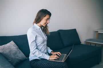 Adult woman working on laptop at home on sofa