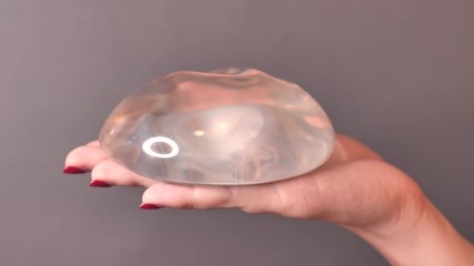Smooth breast implant presented on the girl's hand