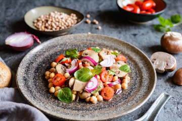 Obraz na płótnie Canvas Vegan chickpea salad with roasted mushrooms, cherry tomatoes and onion