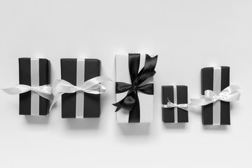 Top view of many boxes of gifts presents in black and white paper with black and white ribbons bows on white background.
