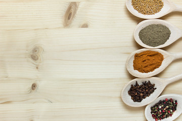 Various herbs on wooden spoons on wooden board background. Photo with copy blank space.