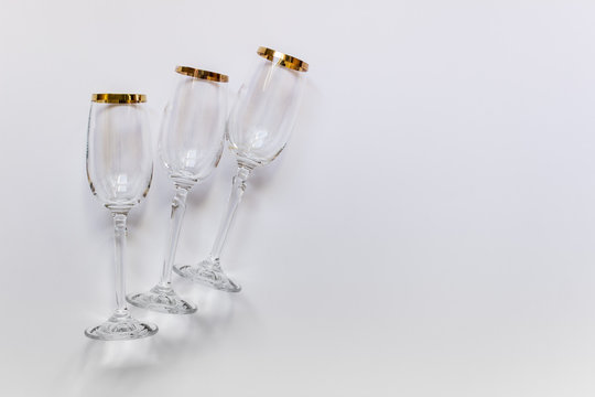 Clear empty wine glasses on white background with golden outline. Photo with copy blank space.