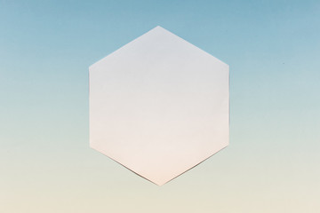 Abstract geometric white paper mockup hexagon on blue gradient tinted background.