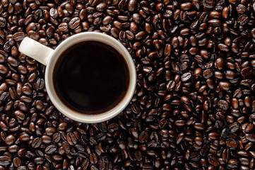 Dark roasted coffee beans with mug of coffee