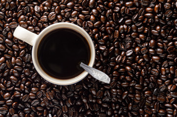 Dark roasted coffee beans with mug of coffee