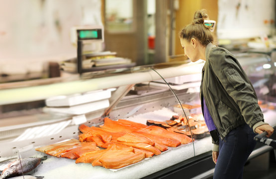 Woman shopping for fresh fish seafood in supermarket retail store	