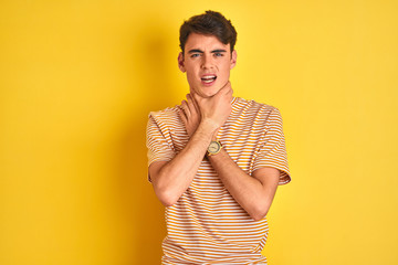 Teenager boy wearing yellow t-shirt over isolated background shouting and suffocate because painful strangle. Health problem. Asphyxiate and suicide concept.