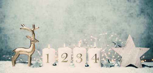 Advent candles 1, 2,3,4 in front of concrete background in the snow with colorful lights and gray...
