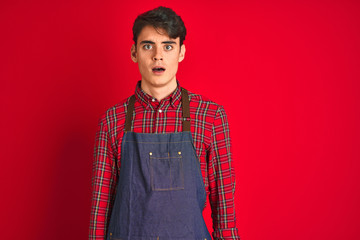 Teenager boy wearing employee apron over isolated background afraid and shocked with surprise expression, fear and excited face.