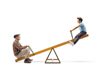 Child playing on a seesaw with his grandfather