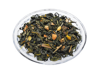 Green leaf tea with pieces of dried ginger, lemon zest and lemongrass herb closeup in glass bowl...