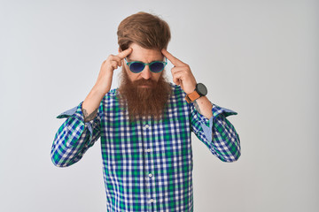 Young redhead irish man wearing casual shirt and sunglasses over isolated white background with hand on head for pain in head because stress. Suffering migraine.