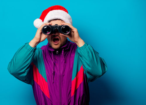 Handsome man in Christmas hat and 90s jacket with binoculars