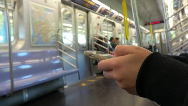 4K. Ultra HD. Close up woman waiting on the train is a good time to do a job on her phone device, using the smartphone to check her email, texting, while waiting for her stop station in New York.