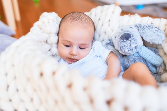 Adorable baby lying down over blanket on the floor at home. Newborn relaxing and resting comfortable with teddy bear