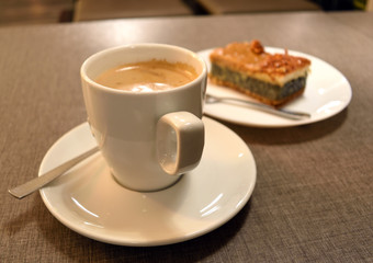 Cup of coffee on a white saucer. Pie with poppy and nuts
