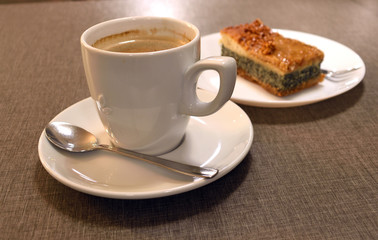 Cup of coffee on a white saucer. Pie with poppy and nuts