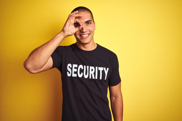 Young safeguard man with security t-shirt over yellow isolated background with happy face smiling...