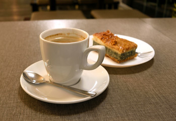 Cup of coffee on a white saucer. Pie with poppy and nuts