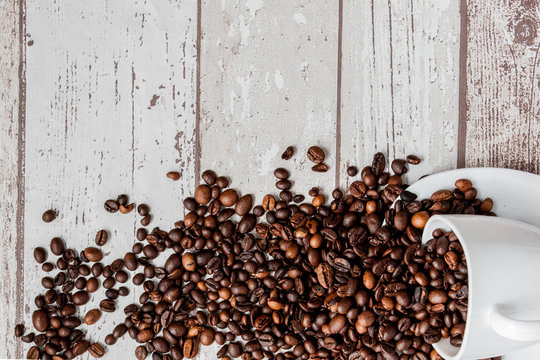 Black coffee in white cup and coffee beans on light wooden background. Top view, space for text