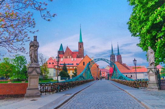 Cobblestone road and Tumski bridge over Odra Oder river, Collegiate Church of Holy Cross and Cathedral of St. John the Baptist in old historical city centre of Wroclaw, evening view, Poland © Aliaksandr