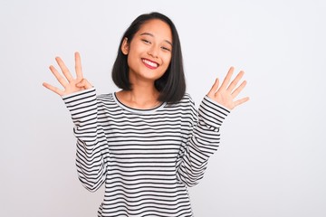 Young chinese woman wearing striped t-shirt standing over isolated white background showing and pointing up with fingers number nine while smiling confident and happy.