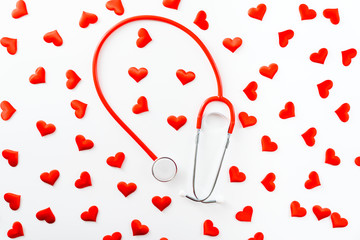 Red stethoscope surrounded by hearts seen from above isolated on white background, coronary heart disease concept.