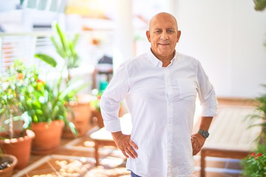 Senior handsome man smiling wih happy and confident. Sitting with smile on face at terrace