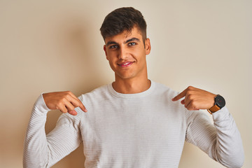 Young indian man wearing sweater standing over isolated white background looking confident with...