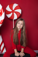 New Year 2020! Christmas, holidays and childhood concept. Merry Christmas, happy holidays! Little blonde girl with a huge christmas candy on an isolated red background. Christmas Eve. Birthday, winter