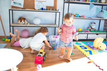 Adorable toddlers playing around lots of toys at kindergarten