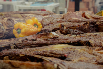 some pieces of tomahawk meat with a yellow pepper on a barbecue grill