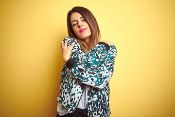 Young beautiful woman wearing casual jacket over yellow isolated background Hugging oneself happy and positive, smiling confident. Self love and self care