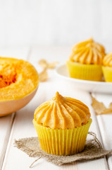 Pumpkin cupcakes with pumpkin-caramel cream wooden Background