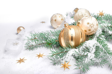Fototapeta na wymiar Shiny sparkling golden Christmas baubles and trinkets, wintertime arrangement. Abstract white background with winter decorations on natural fir twigs under snow. Merry Xmas and a Happy New Year!