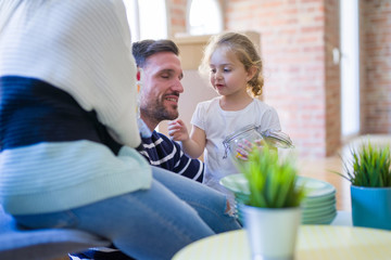 Beautiful family sitting on the floor playing with his kid at new home around cardboard boxes